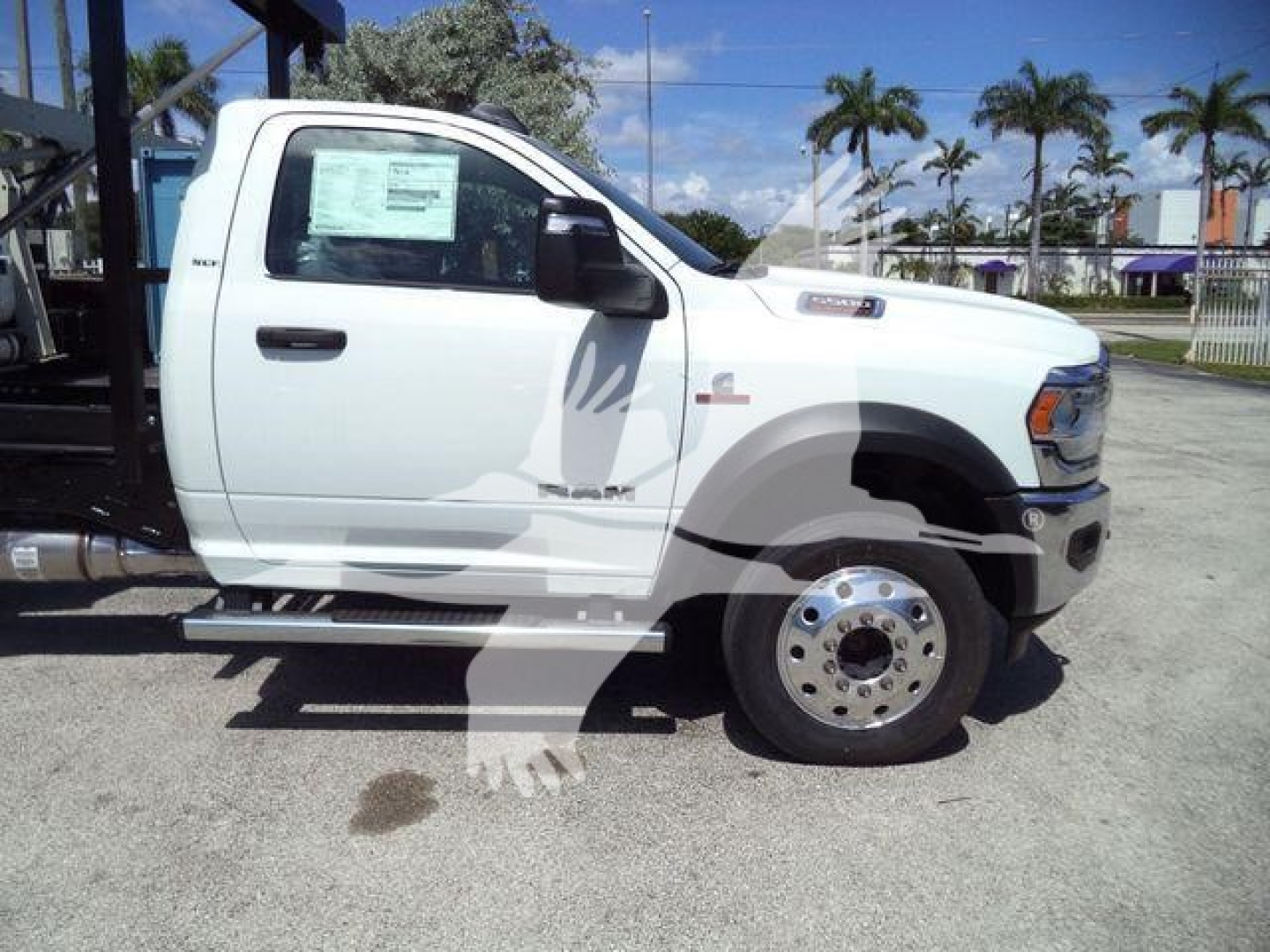 Ram 5500 HD SLT truck side view showing front wheel, chrome hubcap, white cab, and window sticker visible in window.