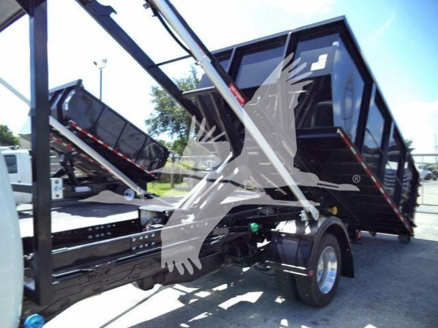 Ram 5500HD SLT truck in service bay with dump bed raised and hydraulic arms visible.