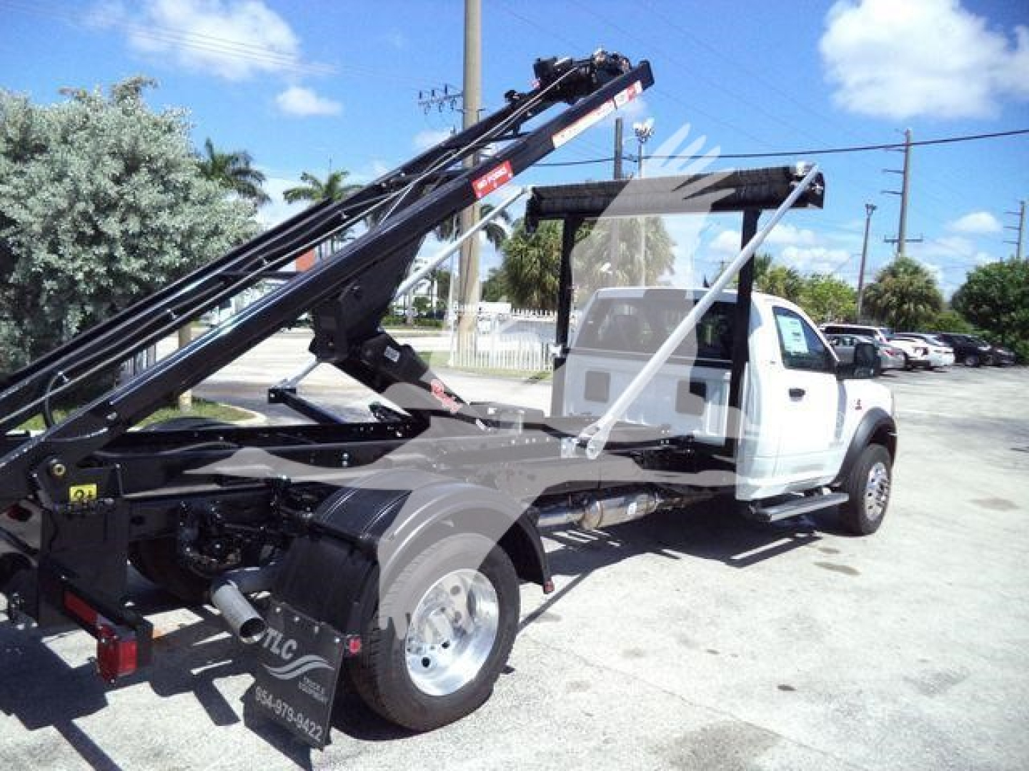 Ram 5500 HD SLT truck with rollback/lift apparatus showing hydraulic arm and flatbed area.