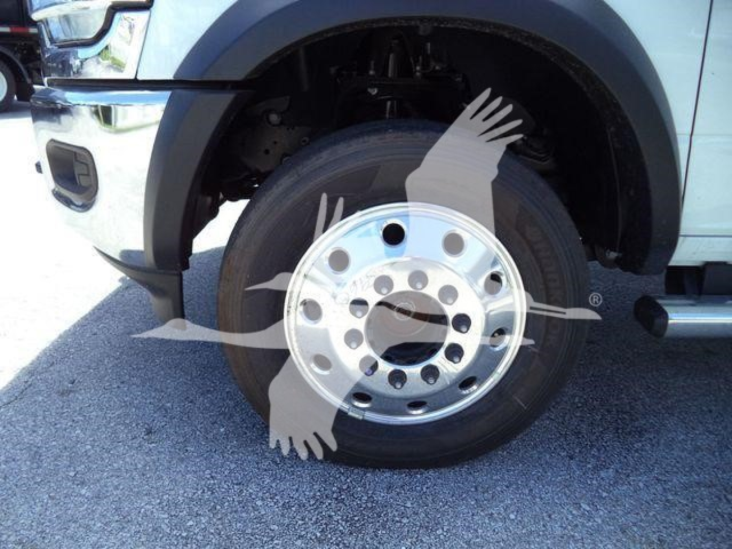 Ram 5500 HD SLT wheel and tire close-up showing chrome steel wheel with multiple circular lug holes and black tire; front fender and bumper partially visible.