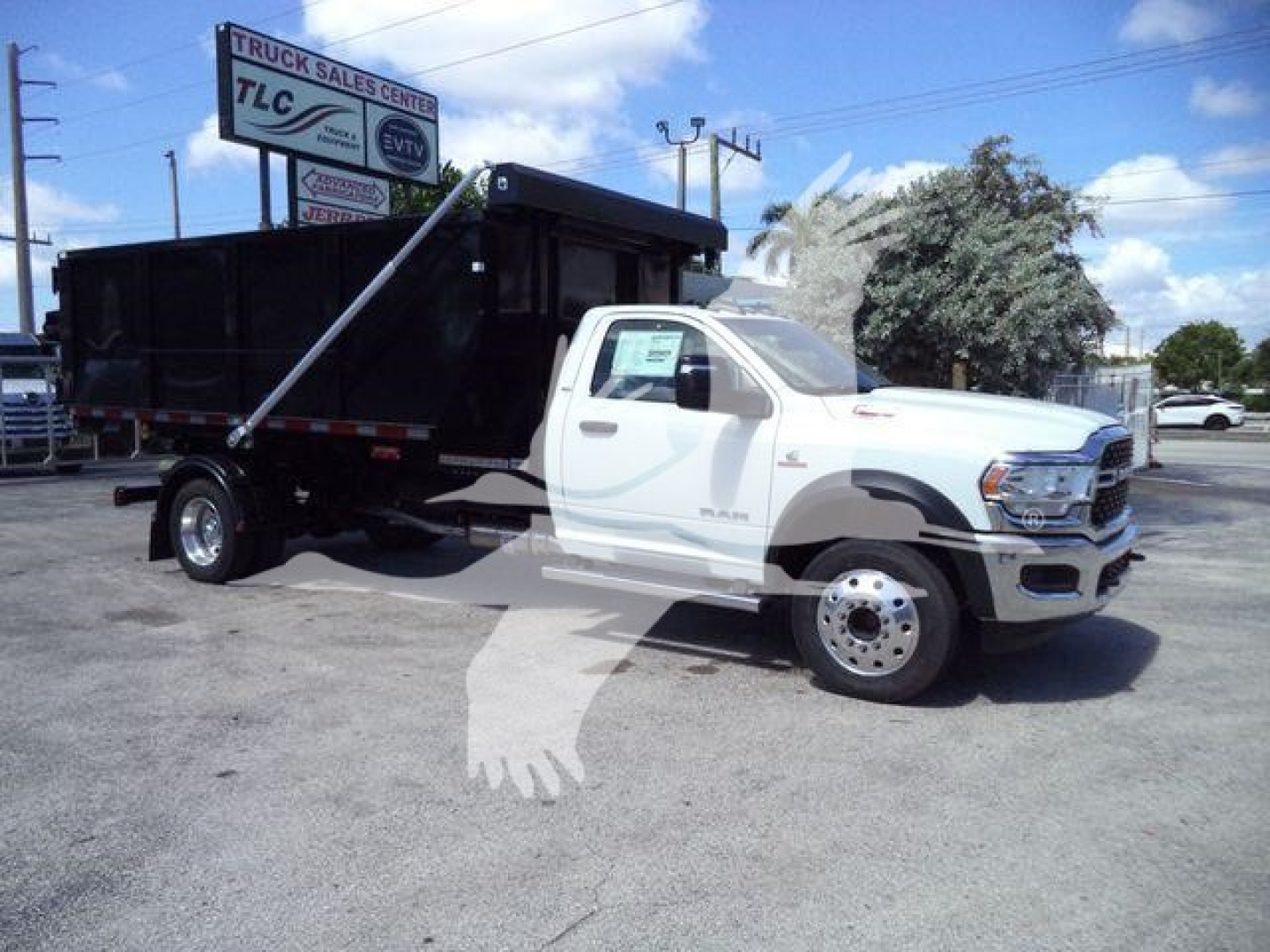 Ram 5500 heavy duty truck with dump bed in a dealership lot, white cab and black dump body, side view showing the truck’s profile.