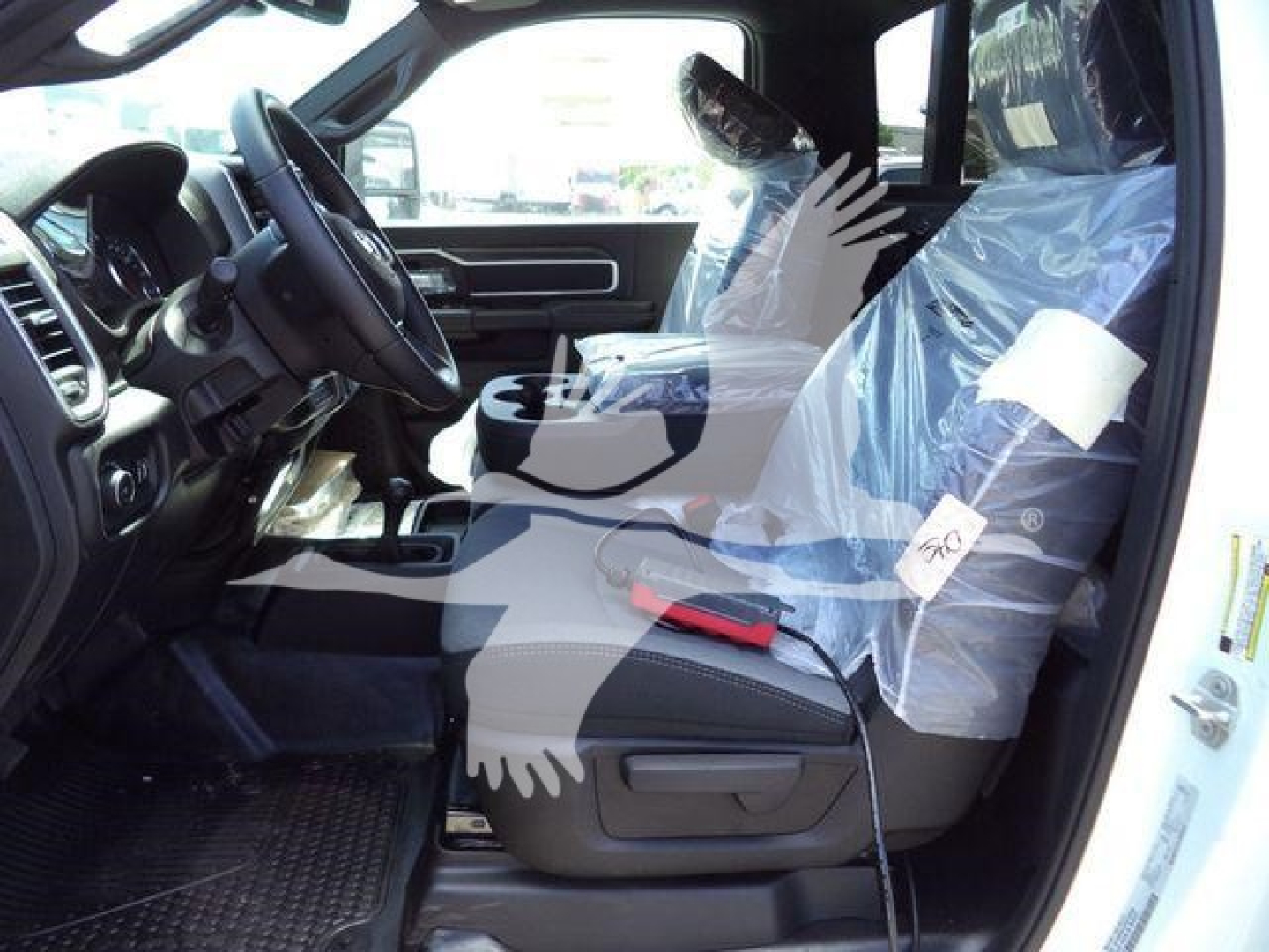 Ram 5500 interior view showing front seats wrapped in plastic and dashboard; steering wheel, center console, and door open; protective coverings indicate new condition.