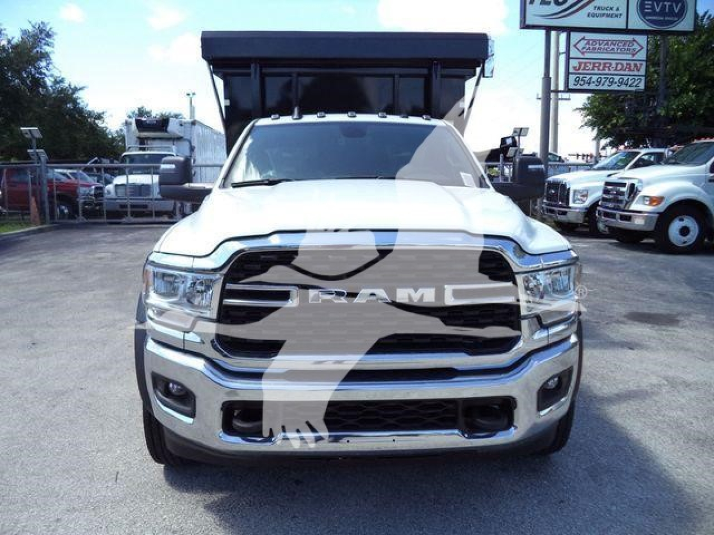 Ram 5500HD SLT front view showing chrome grille with RAM emblem and bumper, headlights, and raised dump bed in background.