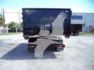 Back view of a black Ram 5500 dump body truck trailer showing two rear doors, taillights, bumper, and contact stickers; no visible engine text.