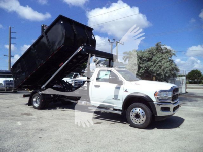 Ram 5500 dump truck side view showing dumping bed raised on hydraulics with white cab and black bed, no visible badges or text.