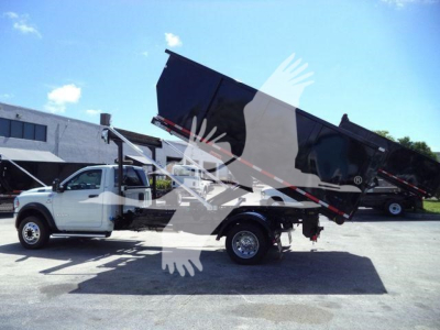 Ram 5500HD dump truck in-service showing dump bed raised over chassis with 4x4 configuration. White cab, black bed, front grille, side mirrors visible.