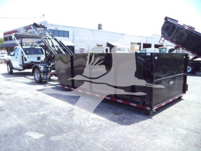 Truck with a large black roll-off container attached; no legible labels visible on the container in this view.