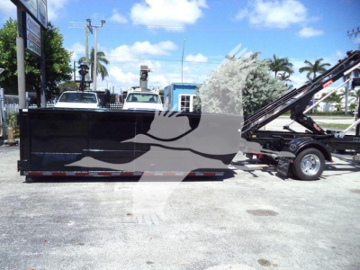 Ram 5500 HD SLT roll-off truck in equipment yard showing long black dump bed and hydraulic hoist with cab at right.