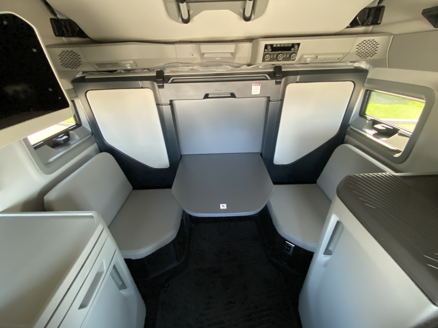 Volvo VNL64T860 cabin interior showing seating area with a foldable table and surrounding light panels.