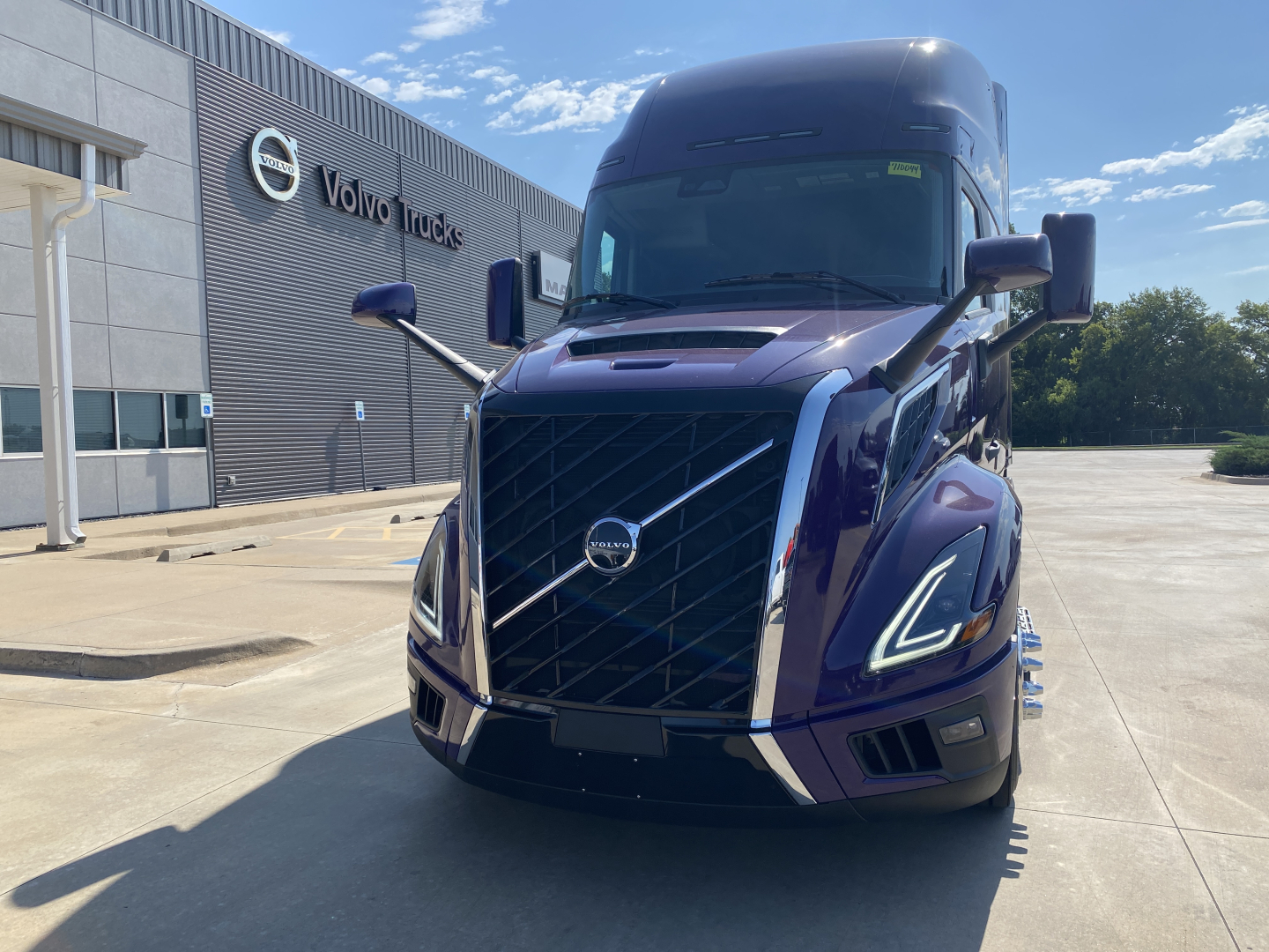 Volvo VNL64T860 truck front view showing prominent grille with chrome accents and Volvo logo, blue exterior, daytime.