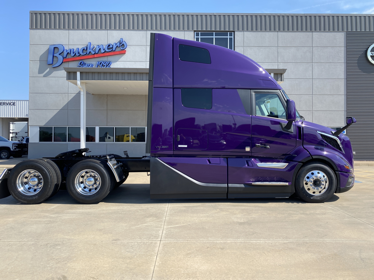 Volvo VNL64T860 truck in purple color parked in front of dealership showing sleeper cab and rear wheels.