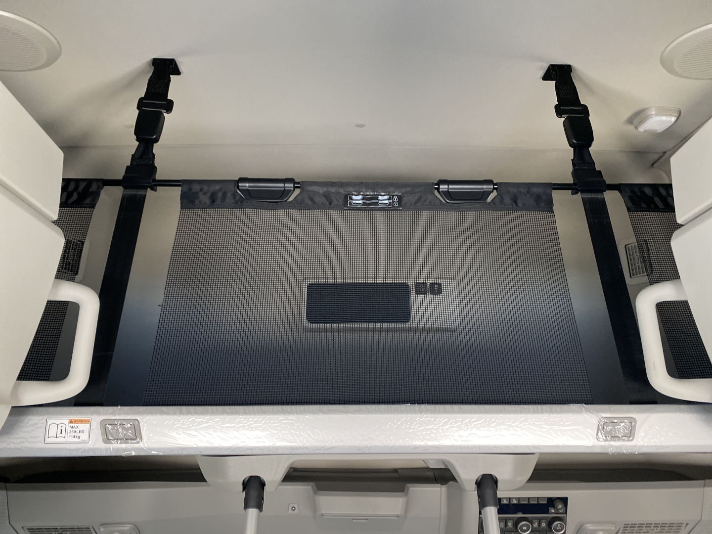 Volvo VNL64T860 cab interior showing sleeper bunk area with fabric panel, tie straps, and storage access in back of cab.