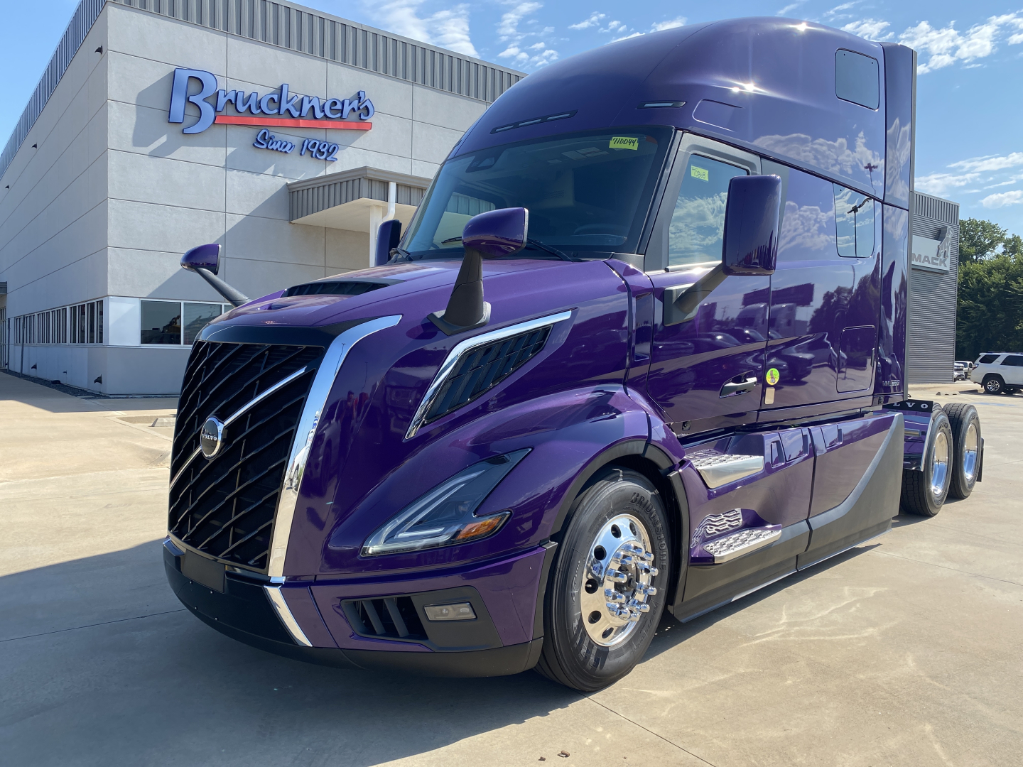 Volvo VNL64T860 tractor in purple paint parked outside dealership showing front grille, headlights, and cab details.