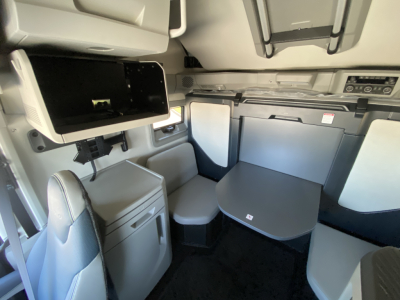 Volvo VNL64T860 cab interior showing sleeper table and storage compartments with light gray upholstery and dashboard area.