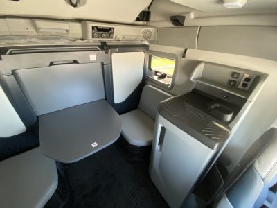 Volvo VNL64T860 cab interior with table, seating area, and compact kitchenette visible.