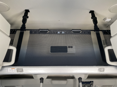 Volvo VNL64T860 cab interior showing sleeper bunk area with fabric panel, tie straps, and storage access in back of cab.