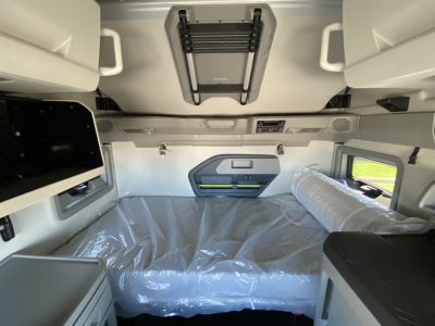 Volvo VNL64T860 sleeper cab interior showing overhead storage, bunk area wrapped in plastic, side cubbies, and control panel.