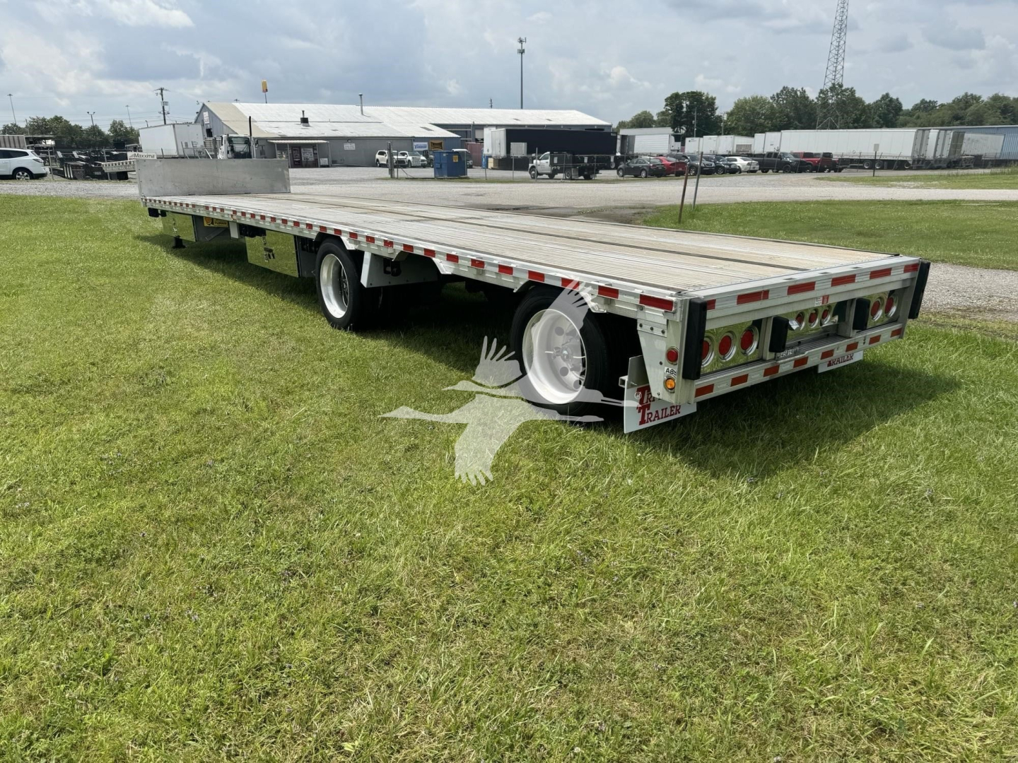 Trailer deck showing flatbed trailer with drop deck design, dual rear wheels, aluminum sides, and rear lighting; stock number 7401 visible in image.