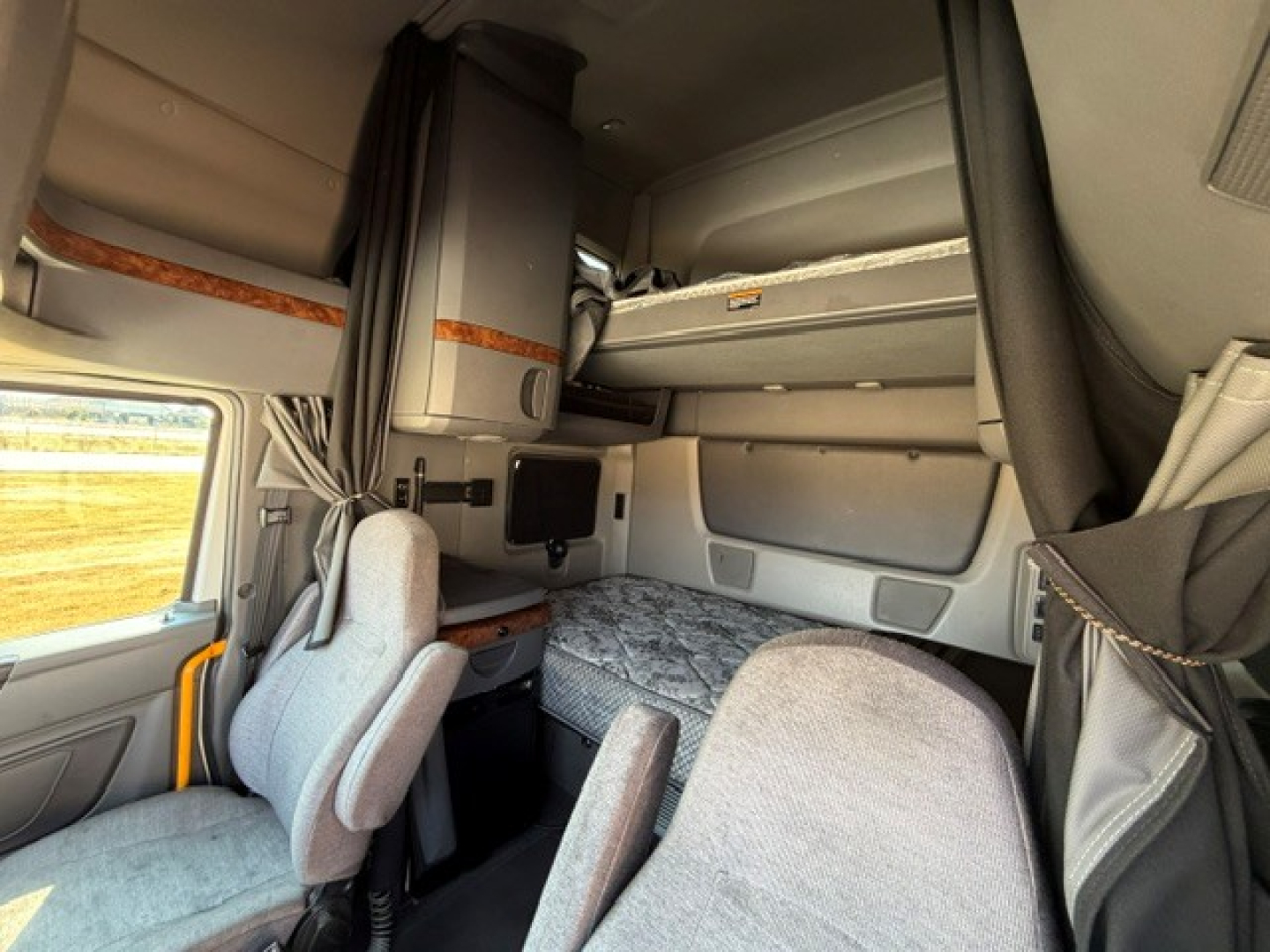 Interior view of a 2021 International LT625 sleeper cab showing bunk bed area, storage shelves, and driver seat with dash area.
