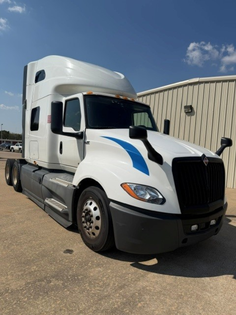 Truck cab exterior of a white 2021 International LT625 sleeper tractor with blue graphics, front grille, headlights, mirrors, and side steps.