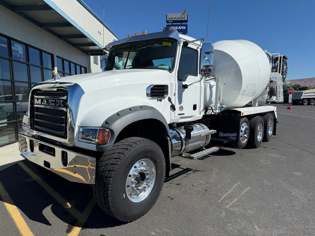 Mack GR64F mixer truck in white showing front grille with MACK badge and cement mixer drum in rear; VIN 1M2GR3GC2VM058533 visible on listing; stock 73737; side steps and chrome mirrors visible.