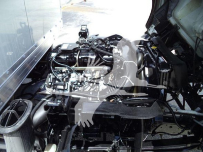 Isuzu NPR-HD engine bay view showing clean engine components and wiring, with various hoses and metal brackets visible.