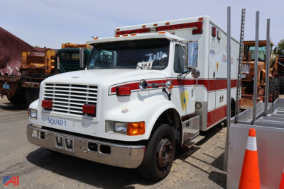 Ambulance front-left view showing International 4700 EMS box with red headlights and text on doors and panels.