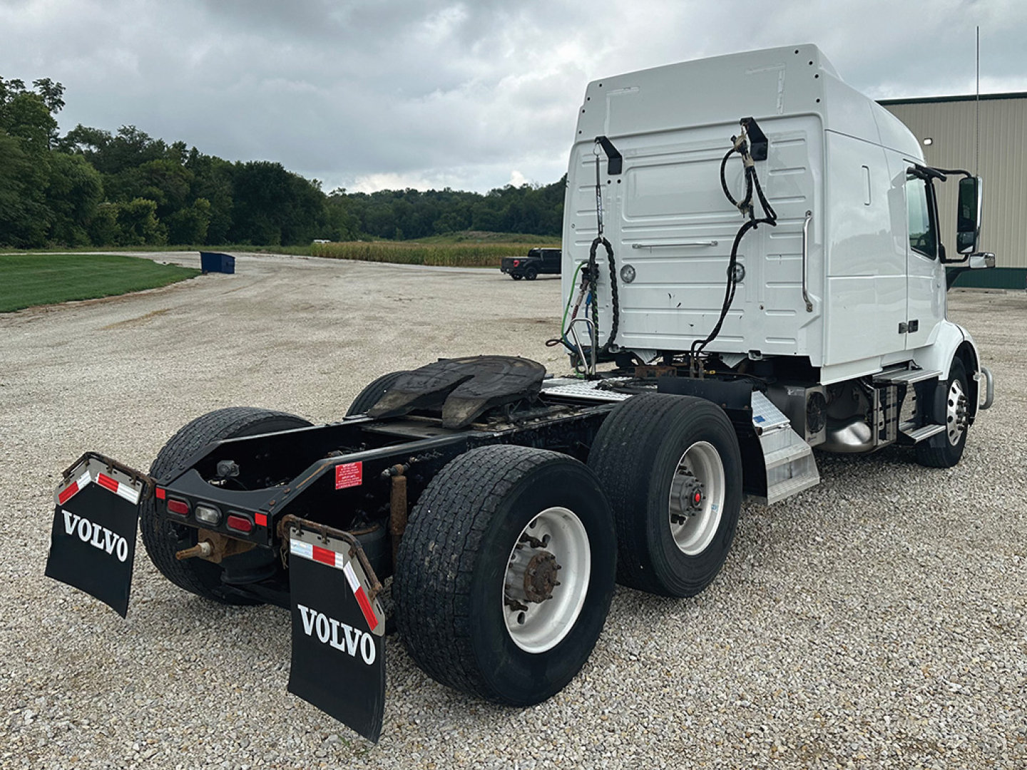 Truck chassis and cab of a 2020 Volvo VNR 640 tractor with white cab, dual rear axles, and Volvo mudflaps in a gravel lot.