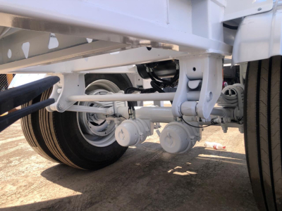 Trailer undercarriage showing dual axles, suspension, and wheels of a cement portable silo trailer.