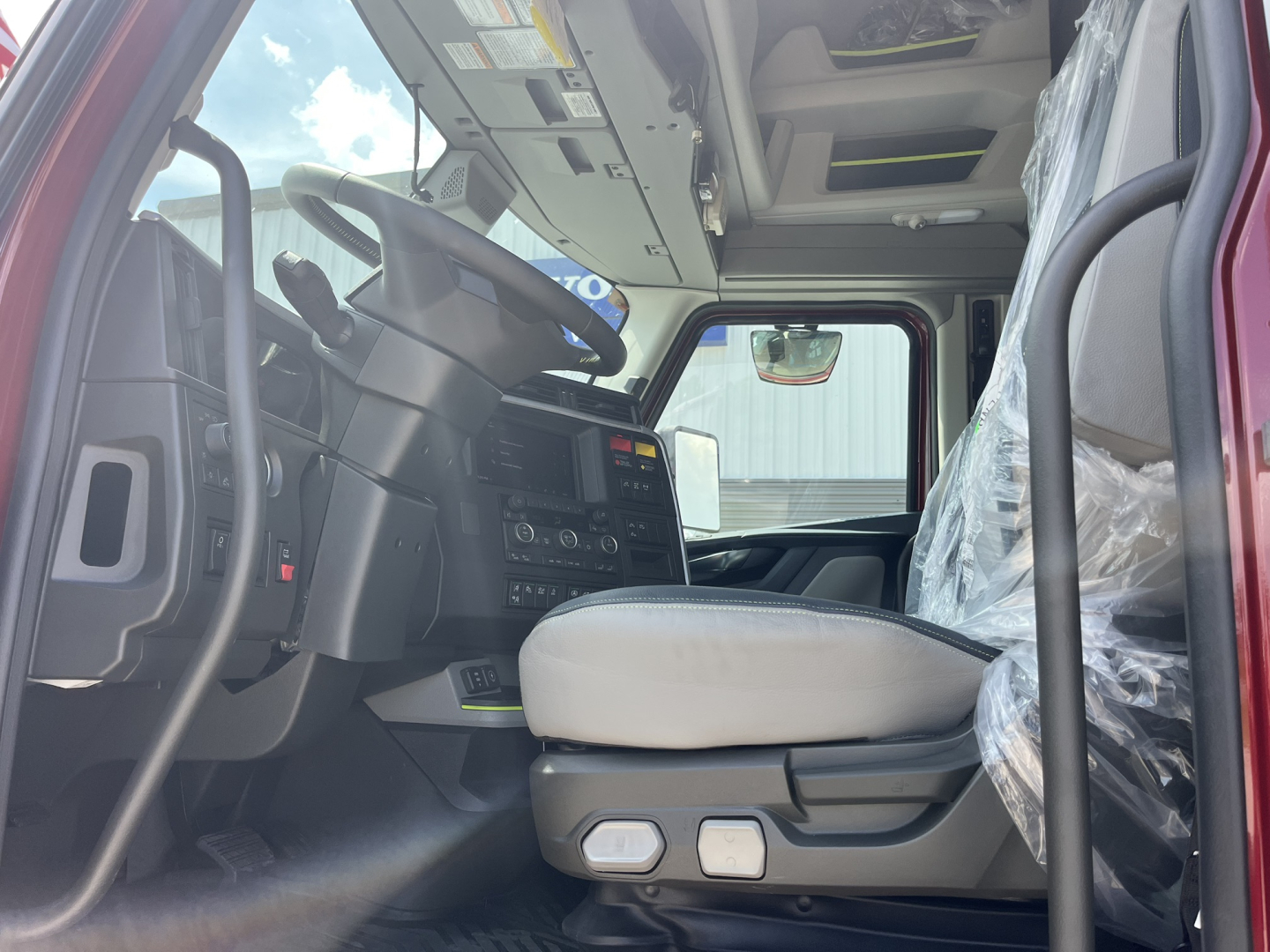  Volvo VNL64T840 truck cab interior view from driver side showing steering wheel, dashboard, and passenger seat. 
