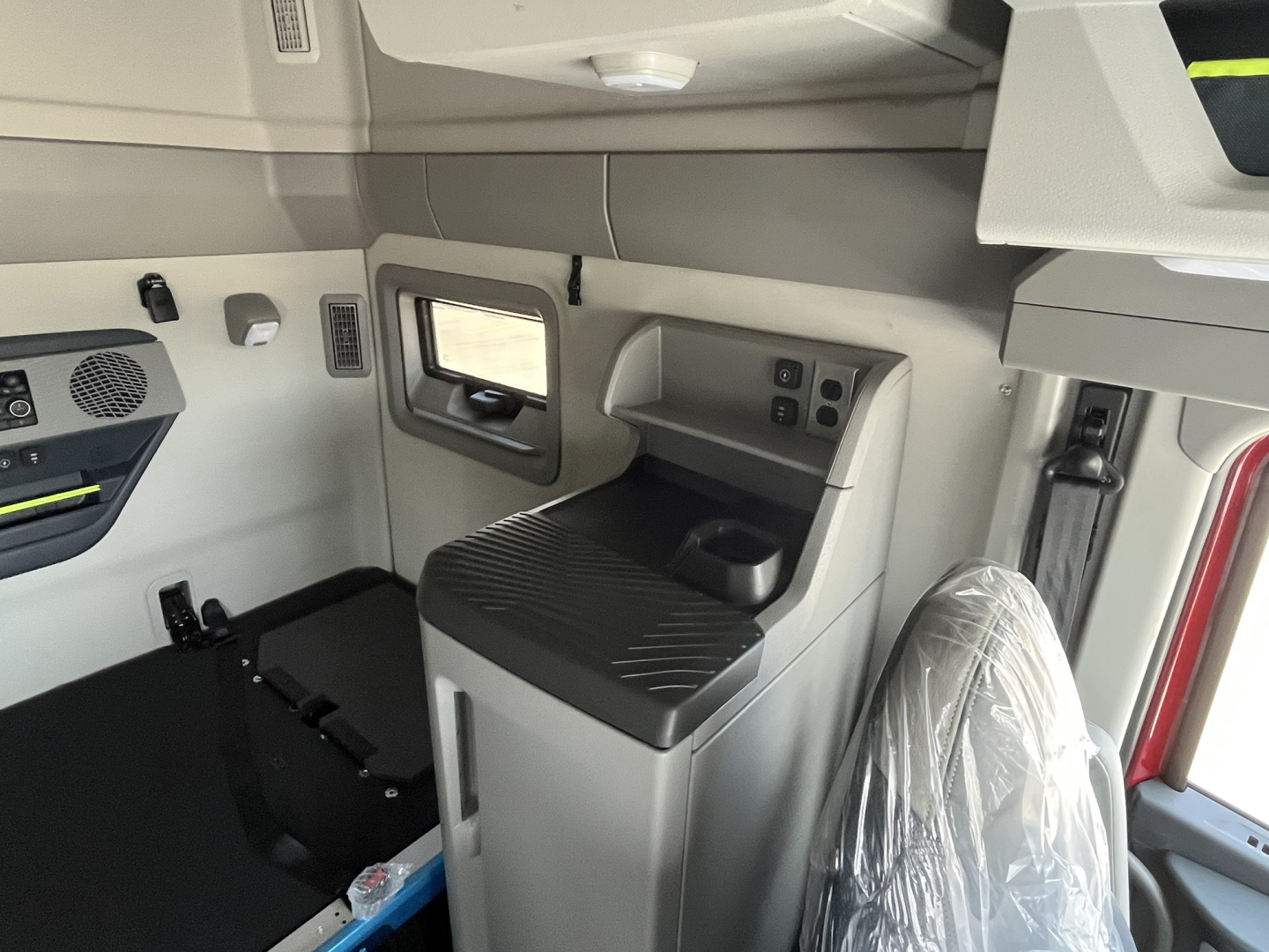 Volvo VNL64T840 cab interior showing sleeper area and controls with plastic-wrapped seat visible.