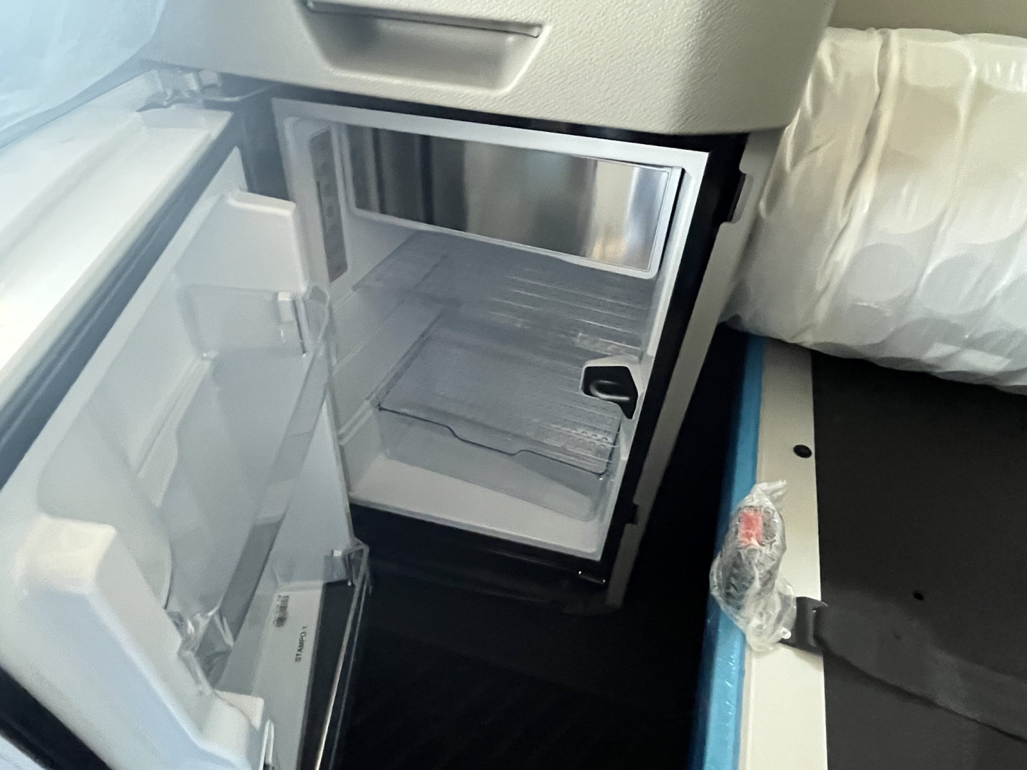 Mini refrigerator in Volvo VNL64T840 cab with open door showing empty shelves and stainless interior.