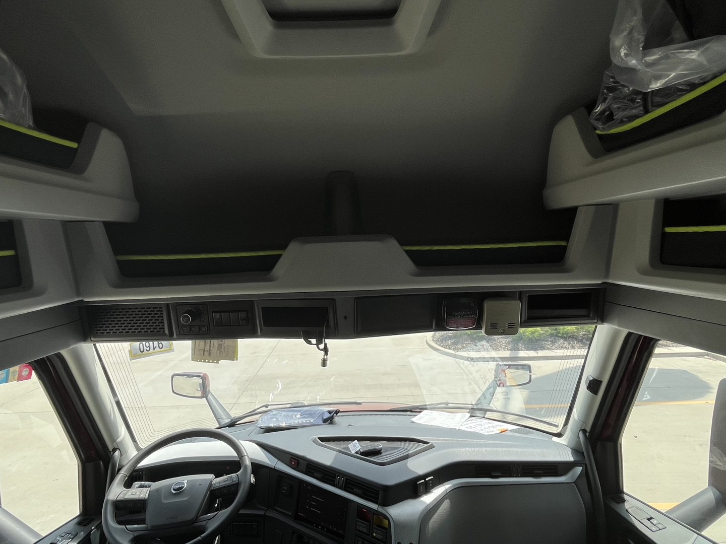 Volvo VNL64T840 interior cab view showing steering wheel and dashboard from driver’s seat with overhead bunk storage and sun visors.