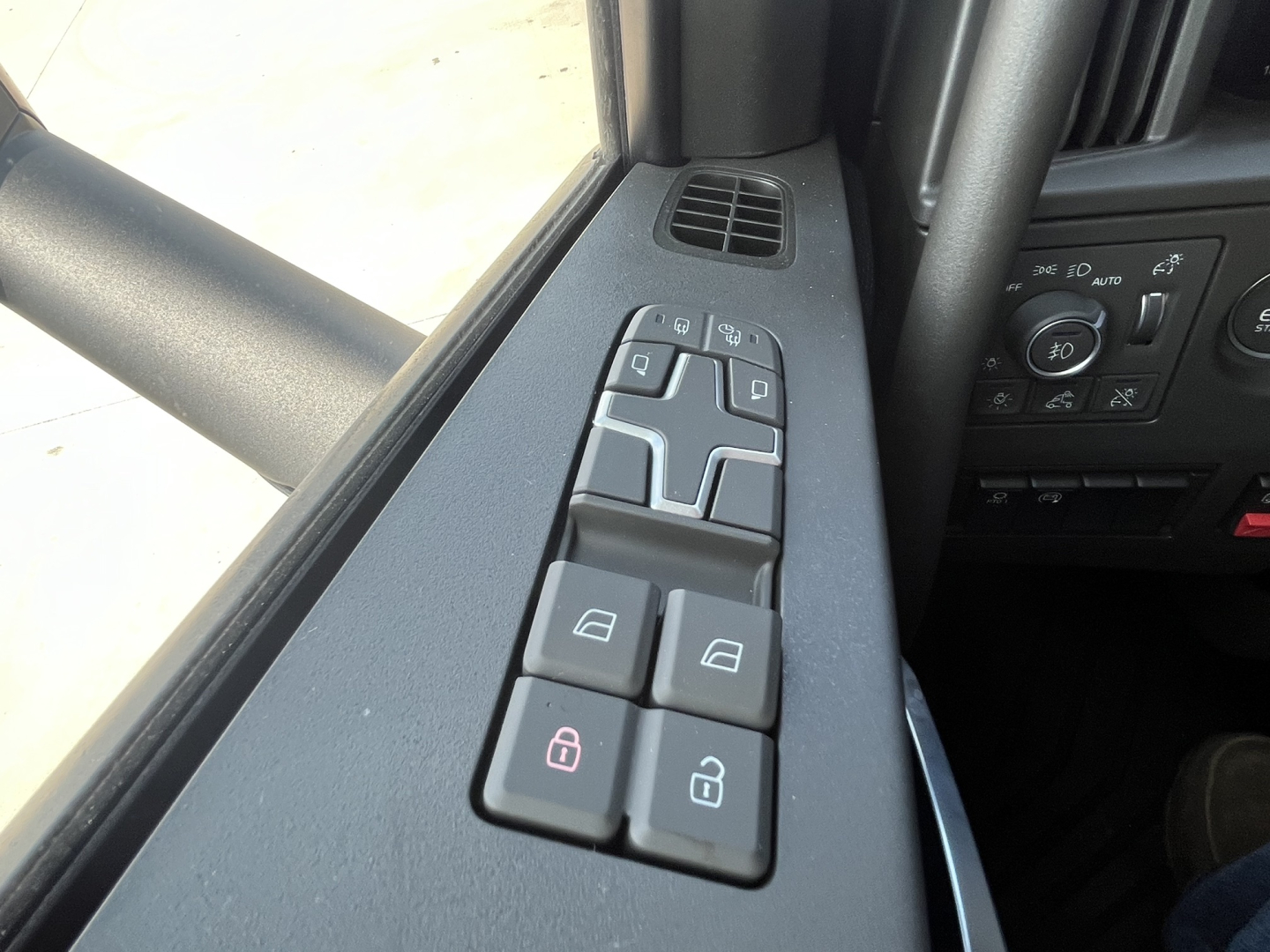 Volvo VNL64T840 interior window panel with control buttons for mirrors and window locks showing four-button cluster and window switch