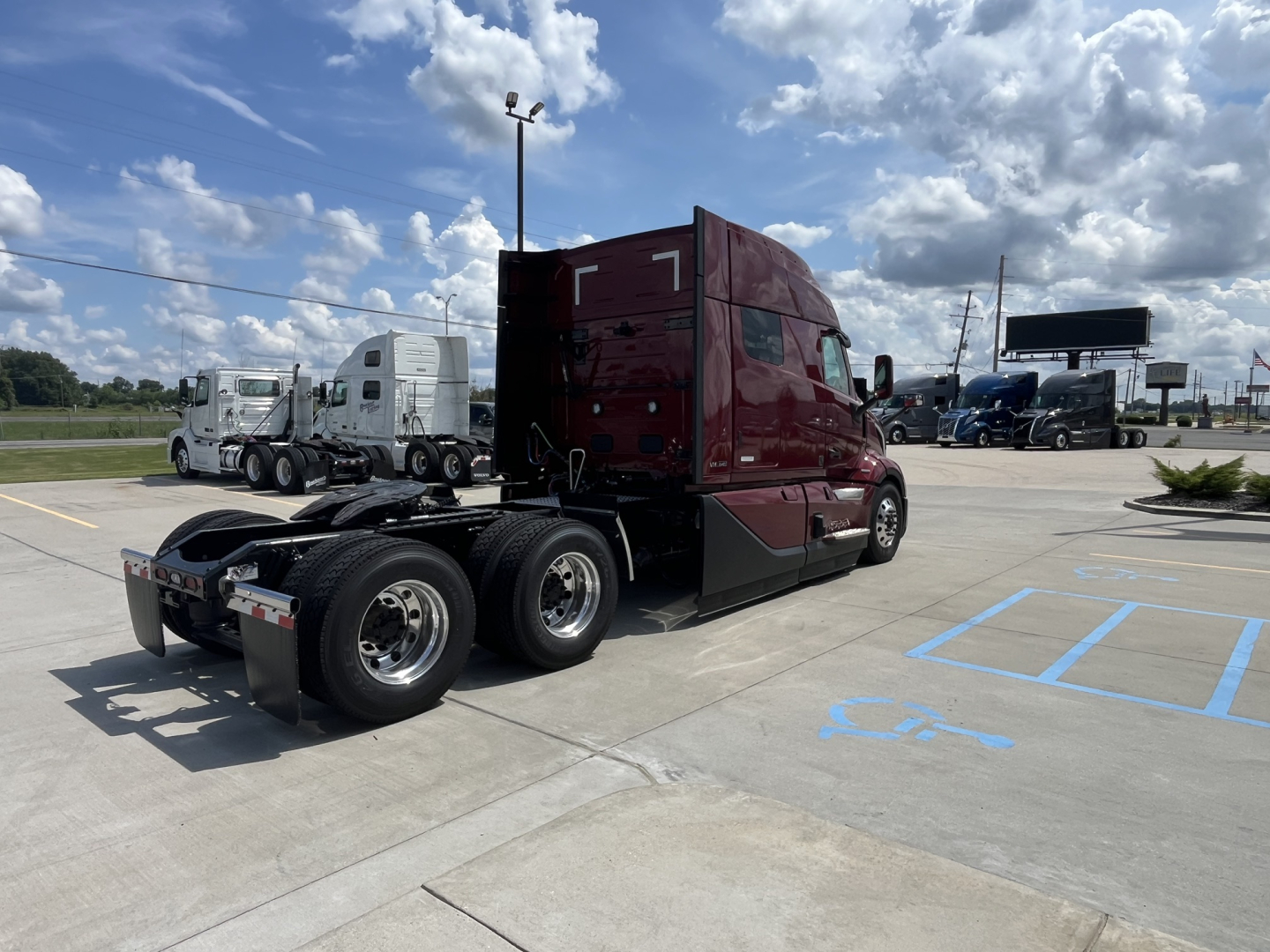 Volvo VNL64T840 truck in showroom lot viewed from rear-left side showing sleeper cab and tandem rear axles.