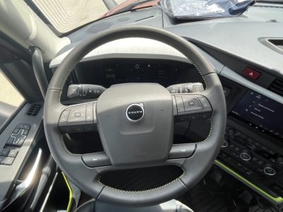 Volvo VNL cabin steering wheel view with digital dash and center console displaying controls.