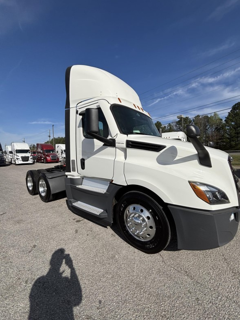 White Freightliner Cascadia 126 day cab truck side view showing sleeper cab, dual rear axles, chrome wheels, daytime running lights, and front bumper.