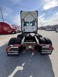 Freightliner Cascadia 126 tractor rear view showing fifth wheel, rear lights, and dual rear axles with mud flaps and dealership plates.