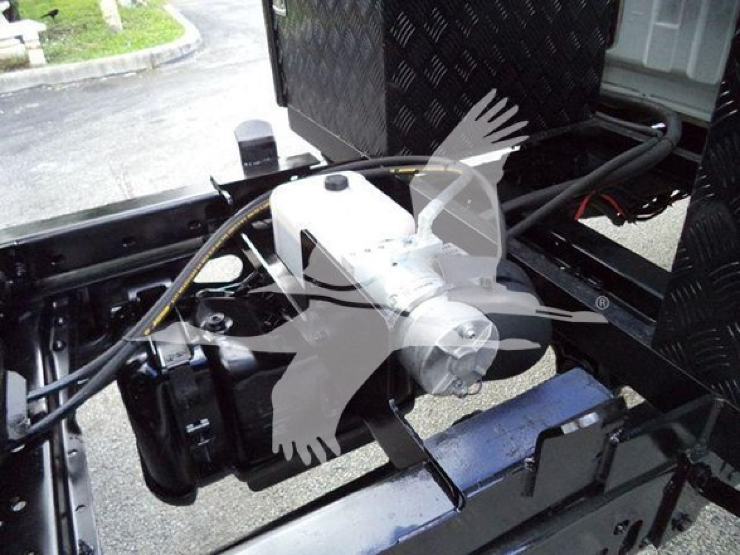 Ford F-550 chassis area showing hydraulic pump/valve assembly and wiring harness in engine bay.