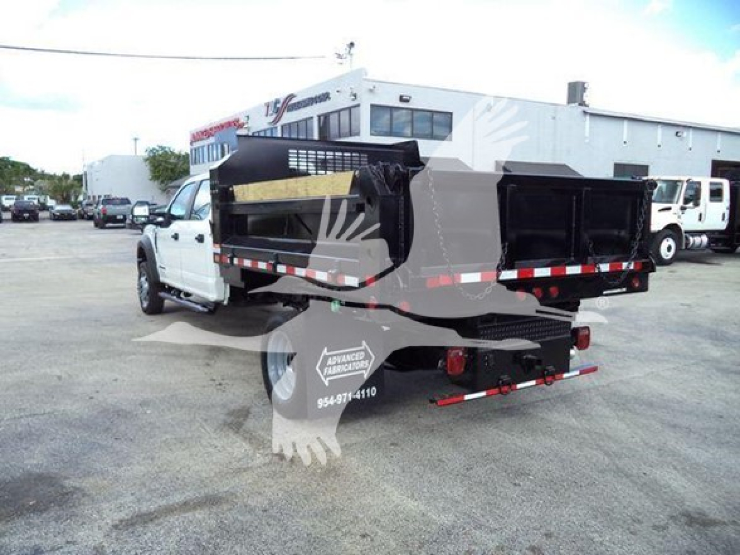 Dump truck bed and rear view of a white Ford F-550 dump truck with black dump box and reflective safety stripes.