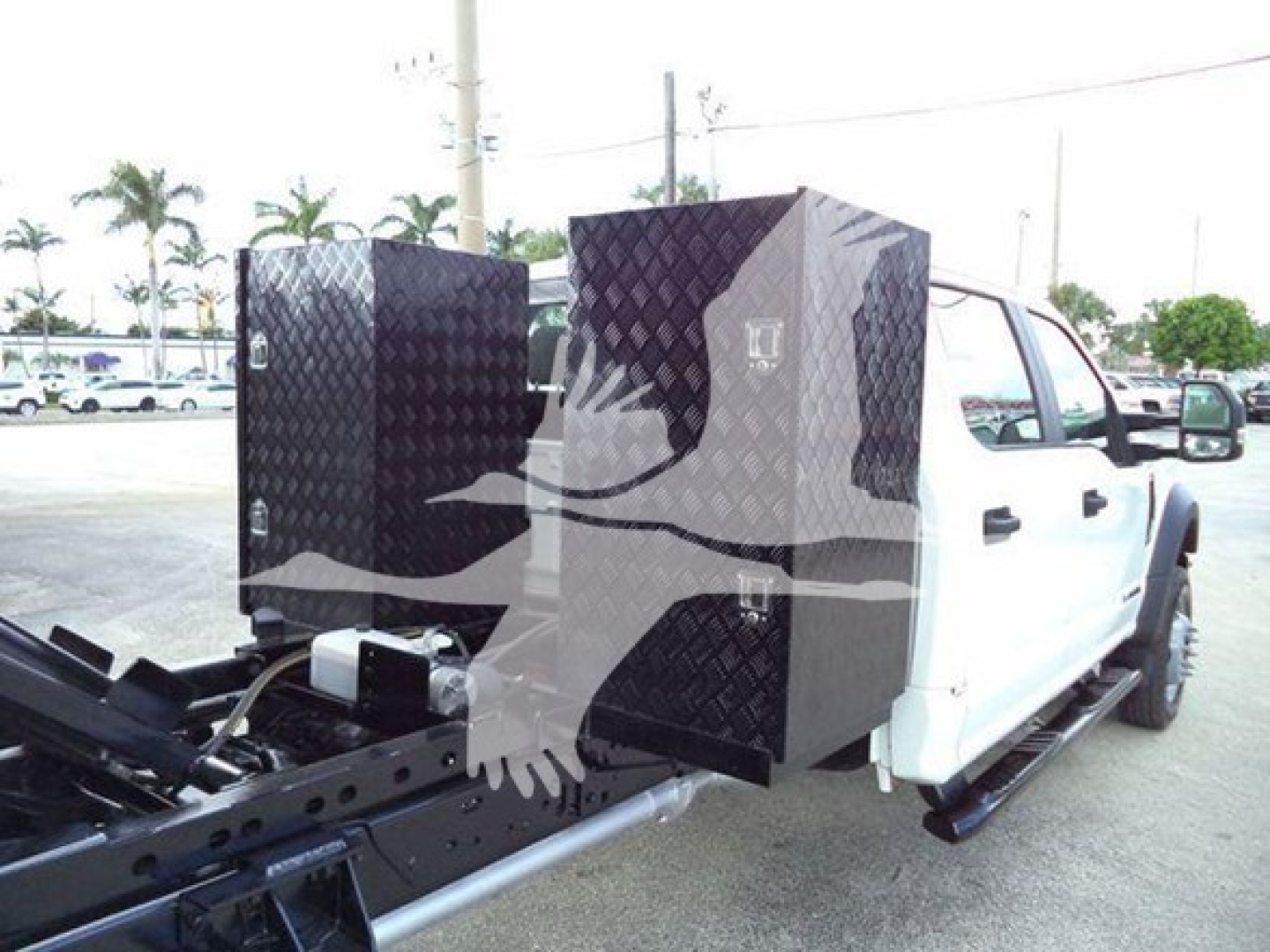 Ford F-550 dump truck from rear side showing diamond-plate tool boxes and hitch area.