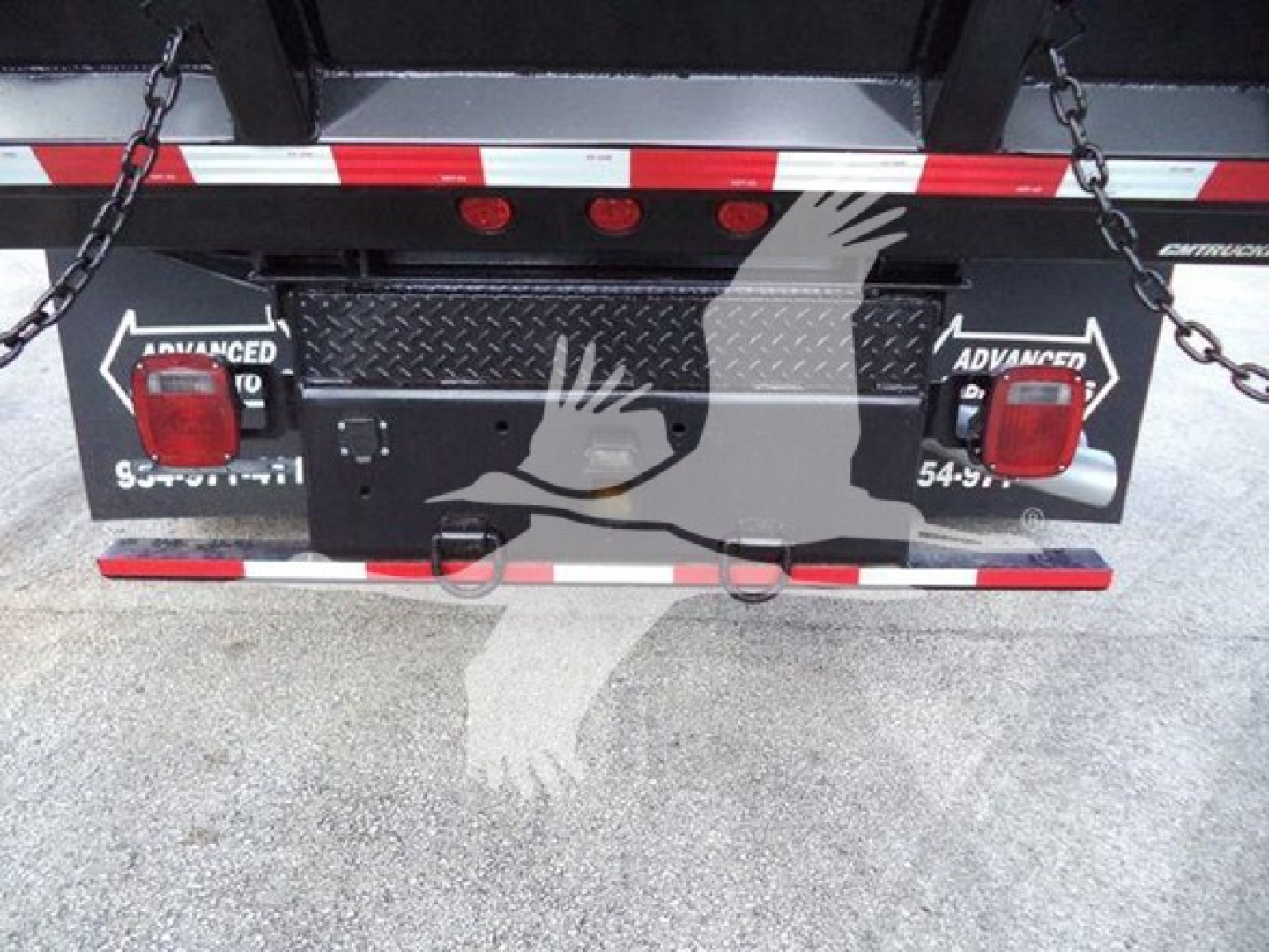 Truck rear showing black utility toolbox, dual red taillights, chain anchors, and diamond plate bed bumper on a Ford F-550 cab chassis in a dump configuration.