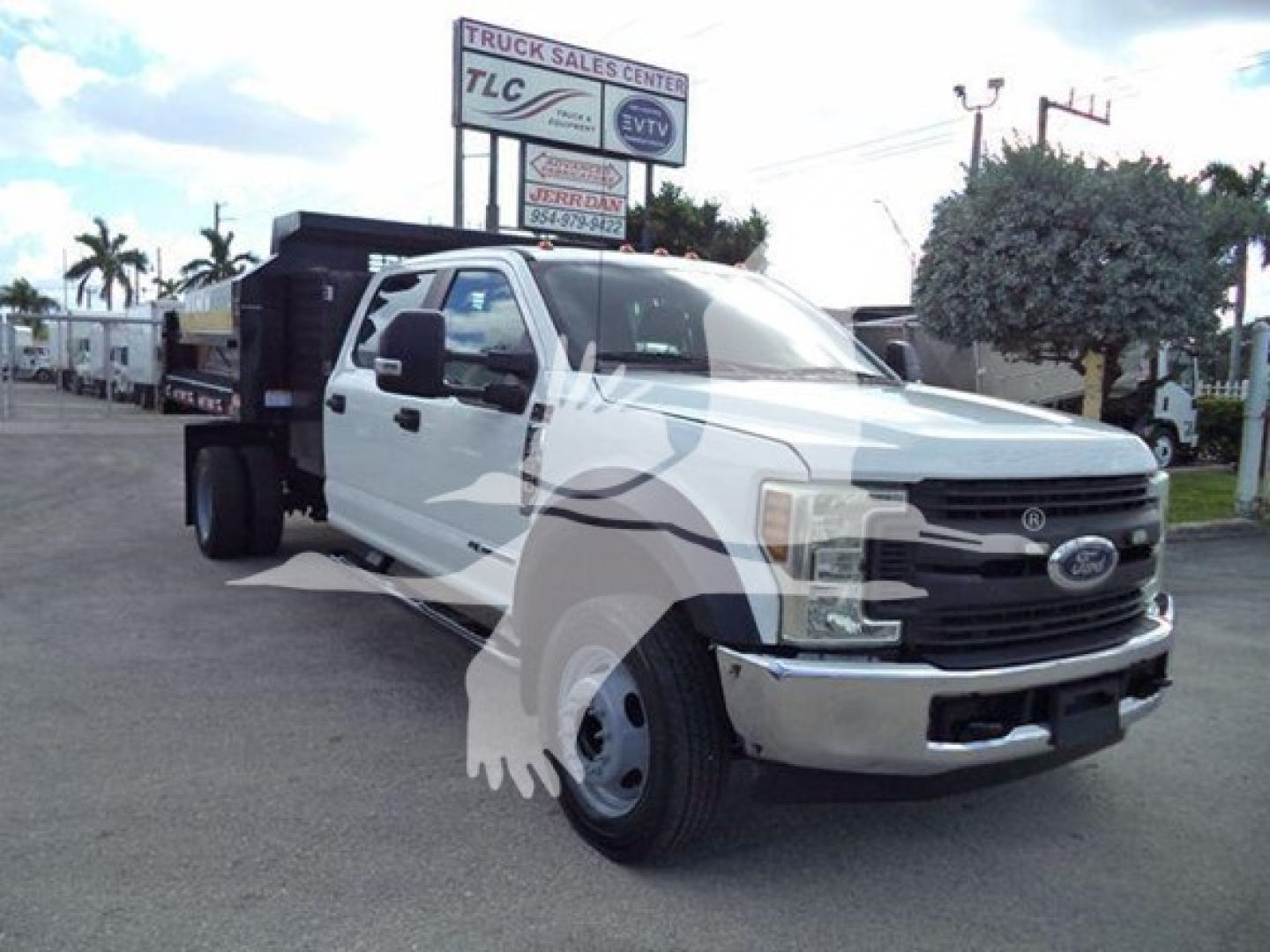 Ford F-550 XL dump truck with white cab and black dump body visible; dealership lot in background.