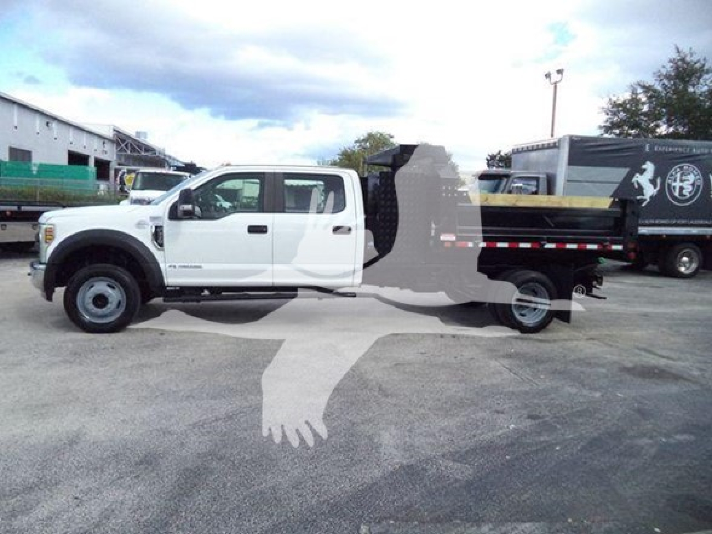White Ford F-550 XL dump truck side view with extended cab and black dump bed. Overlayed watermark silhouette of a handshake logo in the middle.