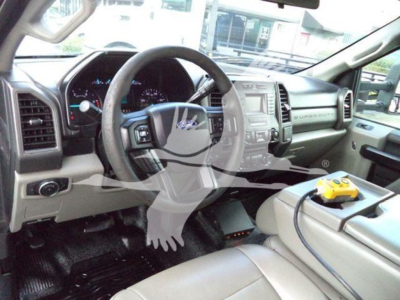 Dashboard and steering wheel of a Ford F-550 cab interior with center console and yellow handheld device on the seat.