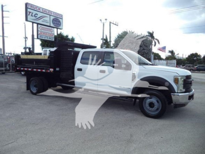 Ford F-550 dump truck side view showing white cab and black flatbed with utility equipment.