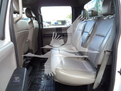 Ford F-550 SuperDuty interior, rear bench seat visible, light gray seats, three-row configuration, view from passenger side, window glare.
