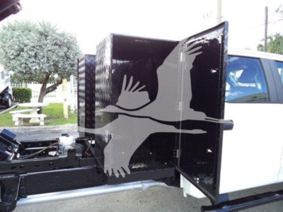 Dump truck cab side with open tool/service box showing interior and chassis components