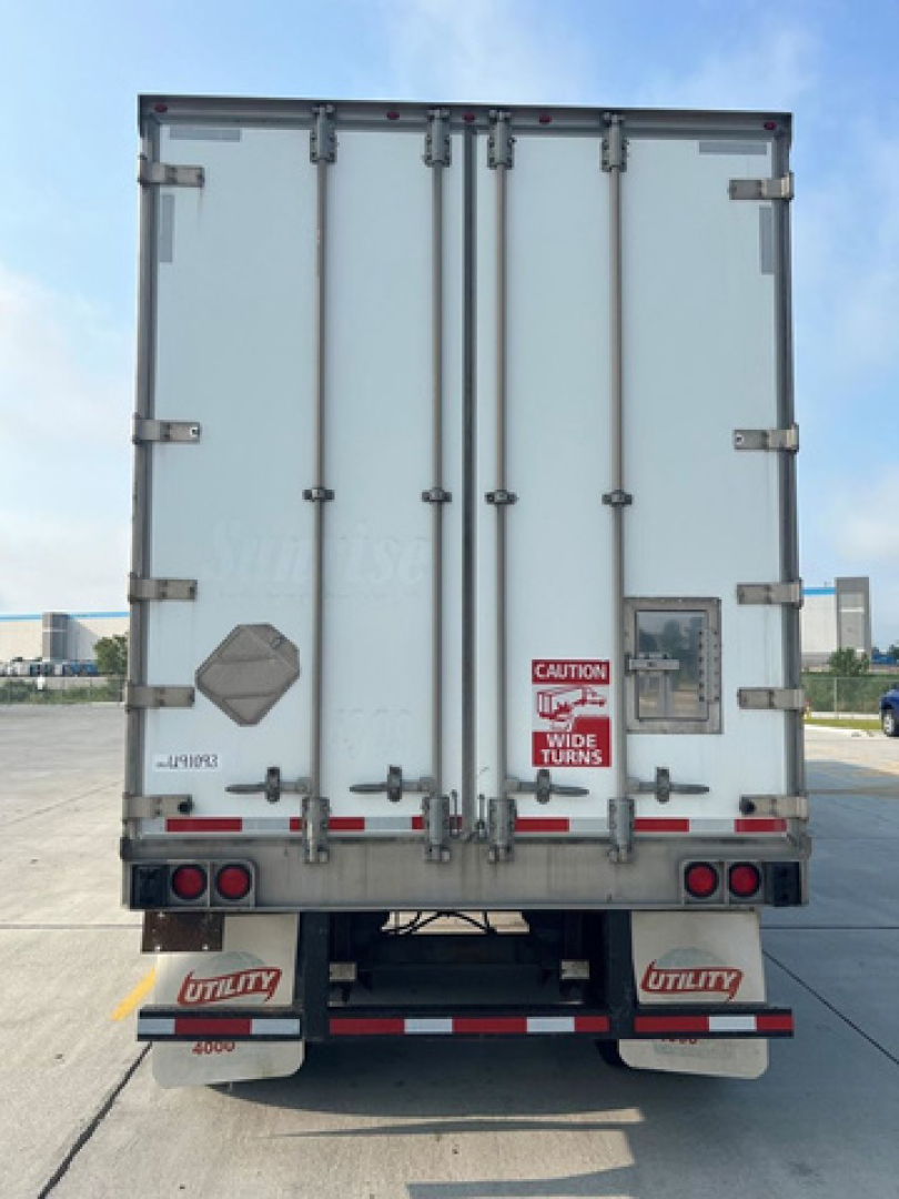 Rear view of a 2014 Utility van trailer with closed double doors, warning sign, latches, and bumper lights. VIN 1UYVS2531EP941519 visible.