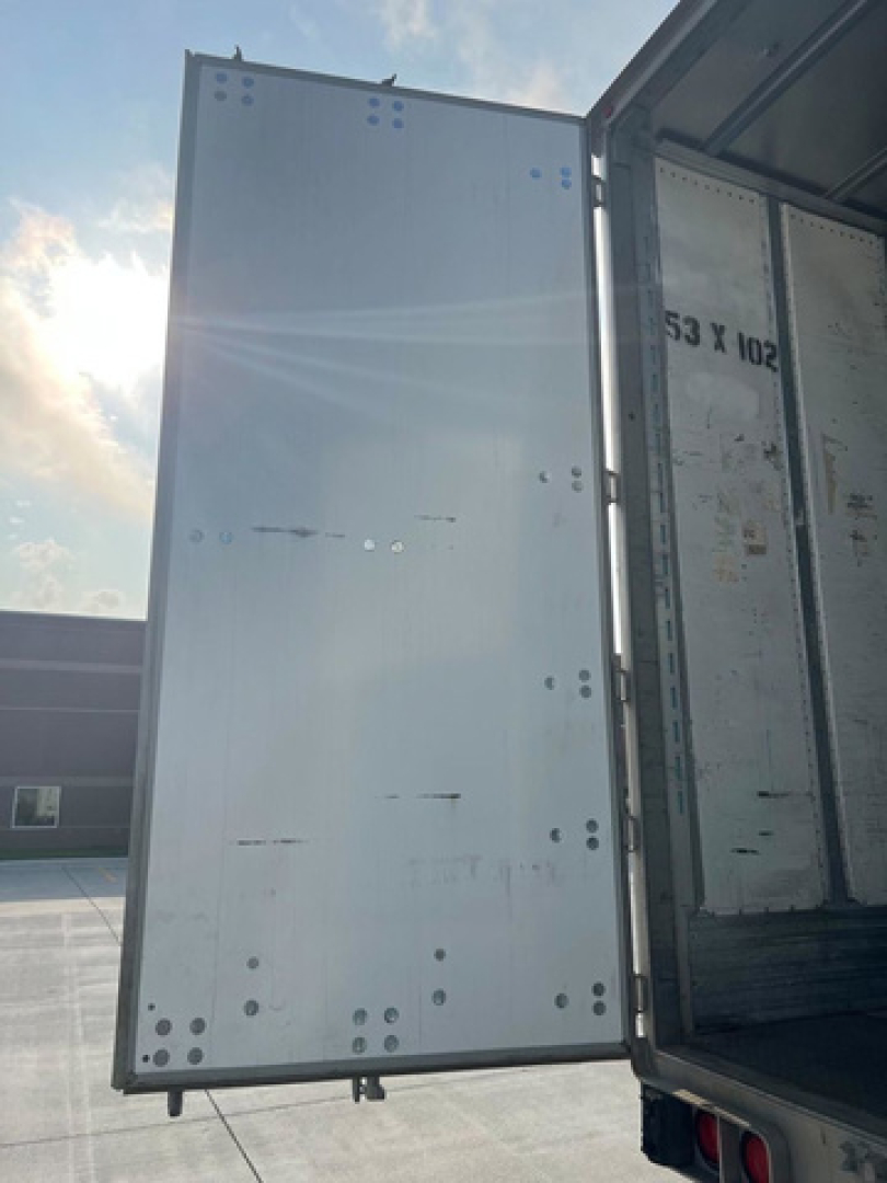 Van trailer interior showing open rear panel and metal interior wall with rivets and screws visible.